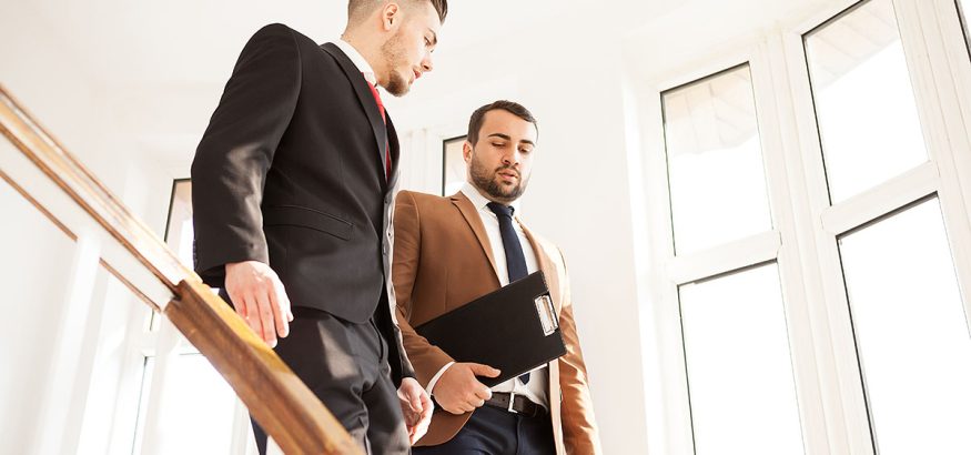 Business partners in suit walking and talking on the stairs of an office building